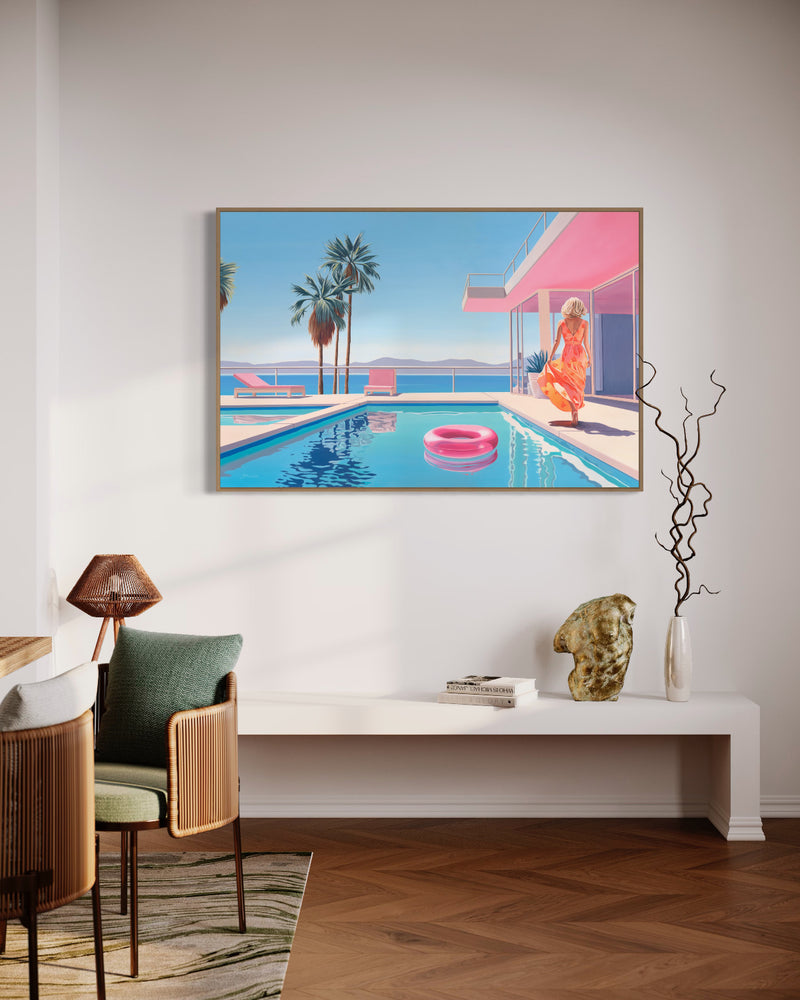 Painting of a serene poolside with a woman in an orange floral dress walking towards a pink-accented modern house. The scene features a blue pool with a pink inflatable ring, pink lounge chairs, palm trees, and an ocean view with distant mountains, all under a clear blue sky. Displayed in a contemporary interior.