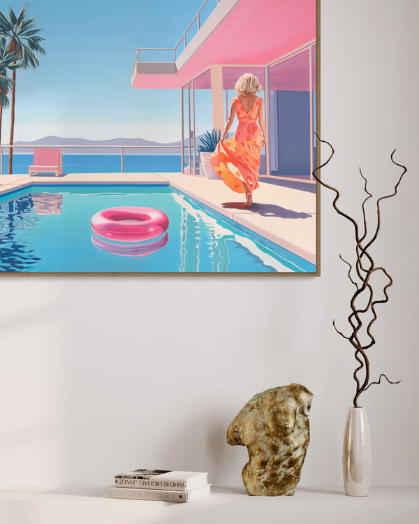 Painting of a serene poolside with a woman in an orange floral dress walking towards a modern, pink-accented house. Features a blue pool with a pink inflatable ring, pink lounge chairs, palm trees, and an ocean view with distant mountains under a clear blue sky. Displayed in a modern interior.